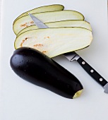 Eggplant being cut into slices for preparation of vegetarian Italian dish