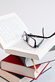 Close-up of stack of books with spectacles on it