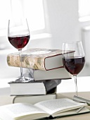 Two glass of red wine with stack of books