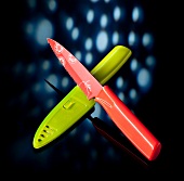Knife with knife cover of red and green coating on black background