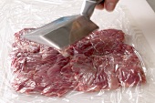Meat being beaten with meat tenderizer, step 3
