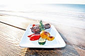 Steak with grilled vegetables on serving plate at beach house with lake view, Westerland