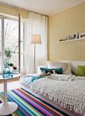 Interior with open sofabed as guest bed & multicoloured striped rug