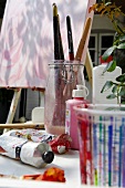 Close-up of tube colour and painting brush in glass jar