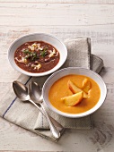 Two bowls of bean soup with noodles and carrot-ginger soup