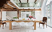 Offener Wohnraum in Weiß mit Holzbalkendecken & verglastem Galeriebereich
