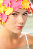 A woman wearing makeup with a colorful bathing cap looking into the camera