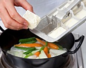 Diced cream blocks placed in pot with vegetables