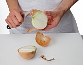 Onions being cut into half and peeled
