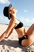 Woman in a black bikini relaxing on the beach in the sun