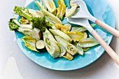 Close-up of fresh zucchini with chicory on blue plate