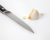 Close-up of knife and garlic clove on white background