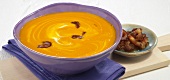 Pumpkin soup in bowl and dates on wooden serving board