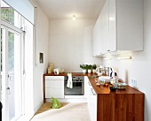 Blick in eine Küche mit weißen Fronten, Holzarbeitsplatte