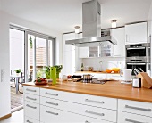 Blick in eine Küche mit weißen Fronten, Holzarbeitsplatte
