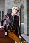 Blonde woman wearing leather jacket sitting with travel luggage