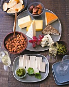 Figs and nuts in bowl and different pieces of cheese on plate