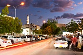 View of city street with cars and mosque in front at night in Nizwa, Oman