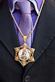 Close-up of person wearing gold chain with picture of Sant 'Efisio, Sardinia, Italy