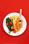 King prawns with spinach, tomato and lemon on plate