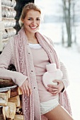 Frau mit Wärmflasche draußen im Schnee Fellstiefel rosa Strickjacke