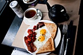 Coffee with fried eggs, toast, bacon sausage and tomatoes on plate