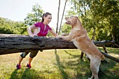Woman in sportswear performing fitness exercise for triceps with dog, smiling