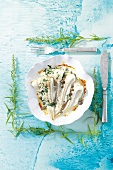Baked plaice fillets with tarragon and caper cream on plate