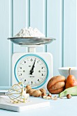 An arrangement of baking ingredients and a pile of flour on an old pair of kitchen scales