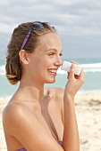 Woman creams her nose with sun blocker