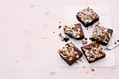 Marzipan brownies with almonds on paper on pink background
