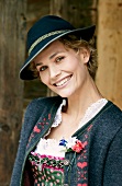 Portrait of pretty woman wearing dirndl dress, coat and hat for Oktoberfest, smiling