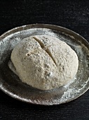 Fermented dough in shape of loaf on round baking tray, while preparing bread, step 6