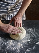 Close-up of hand kneading and folding dough