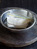 Sour dough in plastic ziploc bag in bowl of water on rustic wooden board