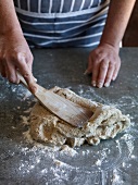 Close-up of hand kneading dough with spatula