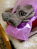 Grey knitted gloves on purple paper