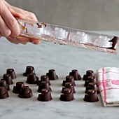 Close-up of hand removing chocolates from mould