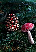 A pine cone and a fabric mushrooms on a Christmas tree