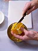Filleting oranges with knife for passion fruit cream with orange salad