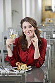 Portrait of pretty woman holding glass of white wine in restaurant