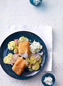 Cod breaded with potato salad and horseradish on plate