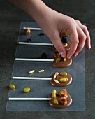 Chocolate lollies being decorated with pine nuts and pistachios