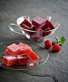 Raspberry jelly cubes and strawberry jelly cubes in glass cup and plate