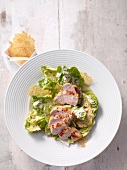 Caesar salad with parmesan chips and chicken breast on plate, overhead view