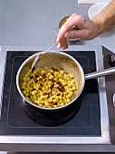 Caramalize pineapple cubes and rum raisins in saucepan