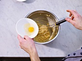 Adding eggs to bowl of dough with whisk