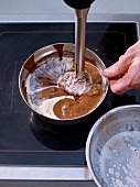 Mixing chocolate, nougat and cream with hand blender in bowl
