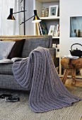 Hand-knitted, grey blanket on sofa