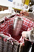 Soup pot in a picnic basket with cushions of red plaid cloth